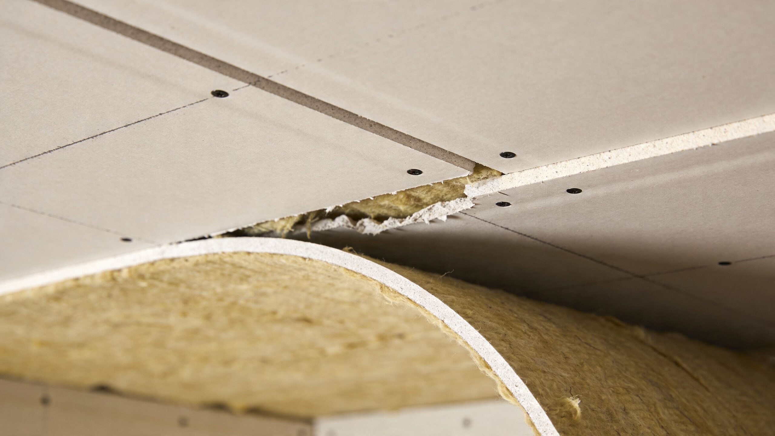 Installation af lyddæmpende gipsplader og isoleringsmateriale i et loft for at reducere støjgener i boligen.